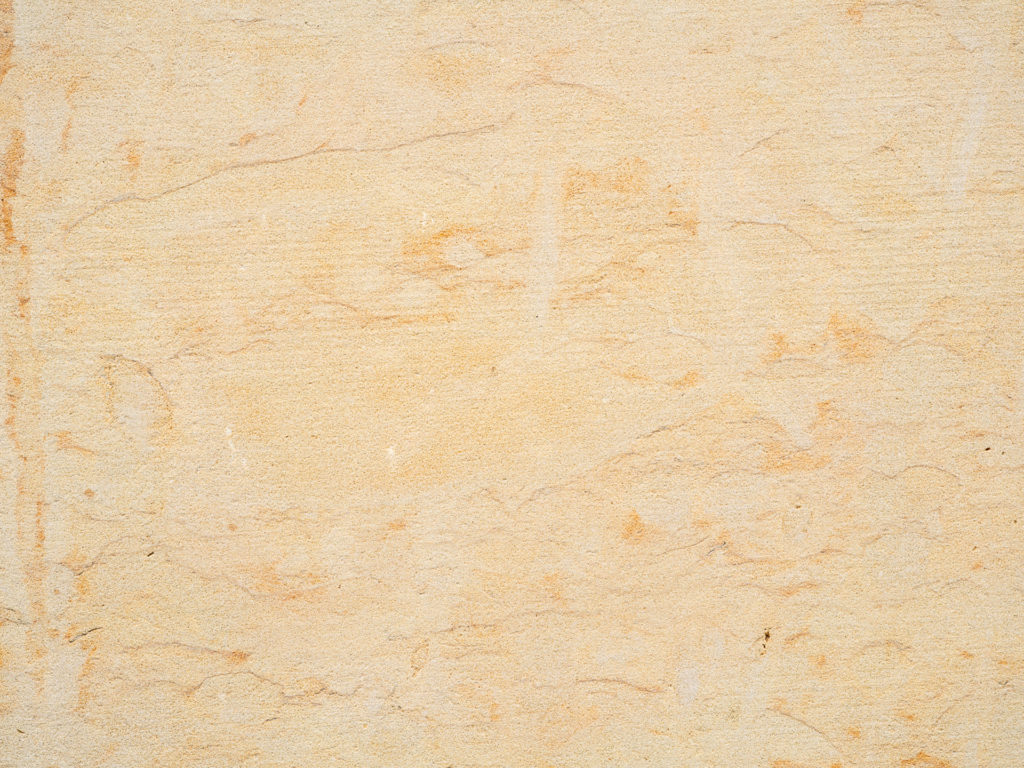Cottaer Sandstein mit einer beigen, strukturierten Oberfläche mit subtilen, unregelmäßigen Linien und schwachen, natürlichen Mustern. Die Textur wirkt rau und leicht uneben und ähnelt entweder Sandpapier oder einer unbearbeiteten Steinoberfläche der Sächsischen Sandsteinwerke. Helle und dunkle Beigetöne verleihen der Szene Tiefe.